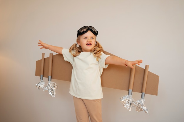 Free photo front view girl playing with cardboard wings