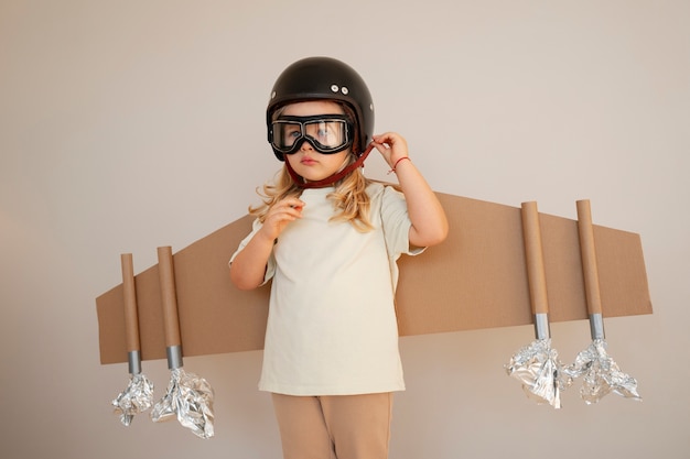 Free photo front view girl playing with cardboard wings