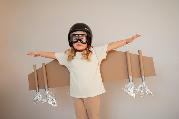 Front view girl playing with cardboard wings