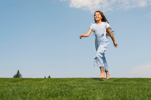 芝生の上で裸足で実行されている正面少女