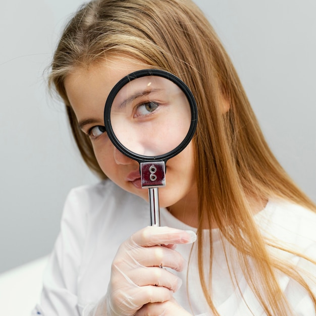 Front view of girl scientist holding magnifying glass