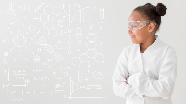 Front view of girl scientist posing with lab coat and safety glasses