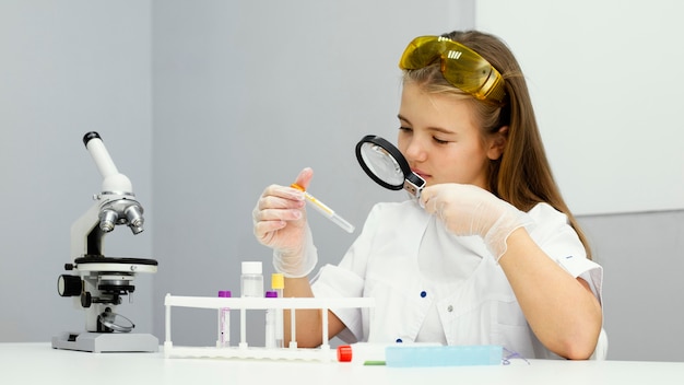 Front view of girl scientist with test tube and magnifying glass