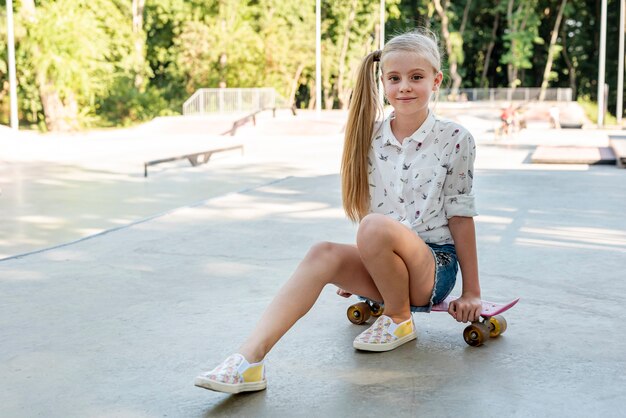 Front view of girl sitting on skateboard