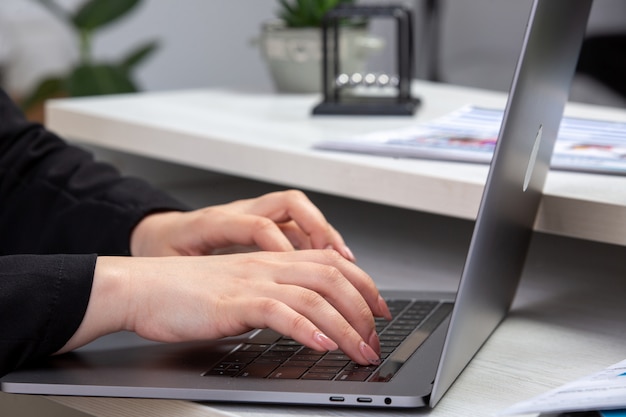 Девушка вид спереди, используя ноутбук перед столом с графиками и графиками и используя ноутбук бизнес-деятельности