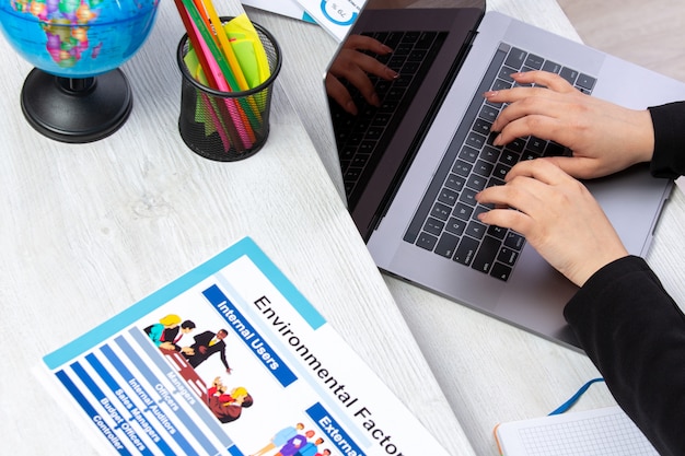 A front view girl using laptop in front of table with schedules and graphics and using laptop job business activity