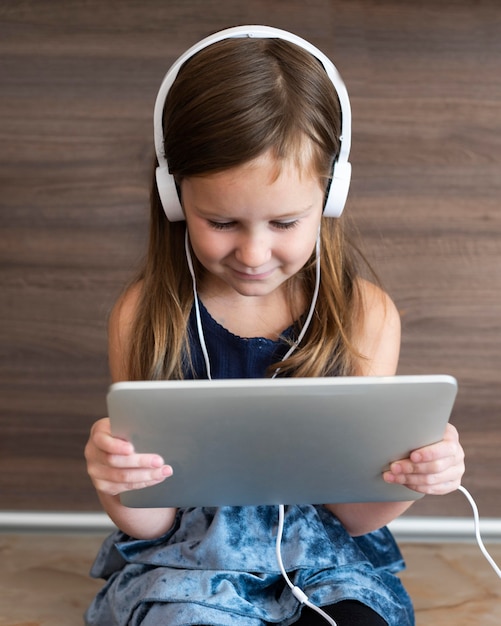 Front view of girl using tablet with headphones