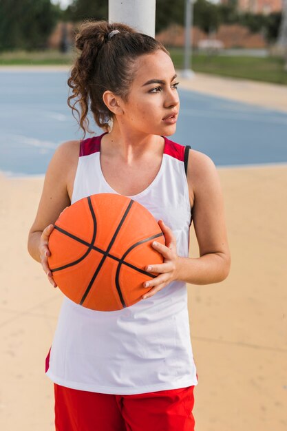 Вид спереди девушки с баскетбольным мячом