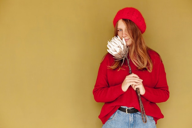 Foto gratuita ragazza di vista frontale con il fiore e la priorità bassa gialla