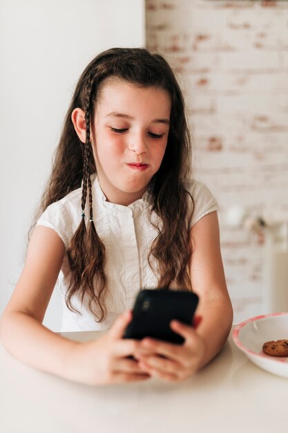 Front view girl with phone and mouth full of cookies