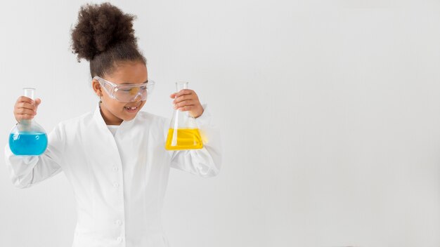 Вид спереди девушки с защитными очками и лабораторный халат, держа трубки с копией пространства