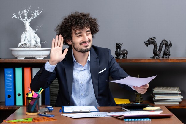 Front view glad businessman hailing someone in his office