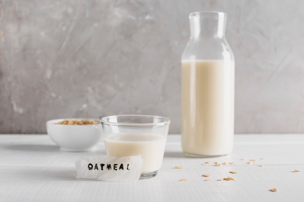 Free photo front view glass and bottle of milk woth oatmeal