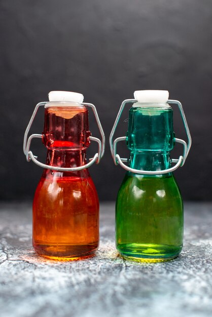 Front view glass cans with liquid inside on a grey table