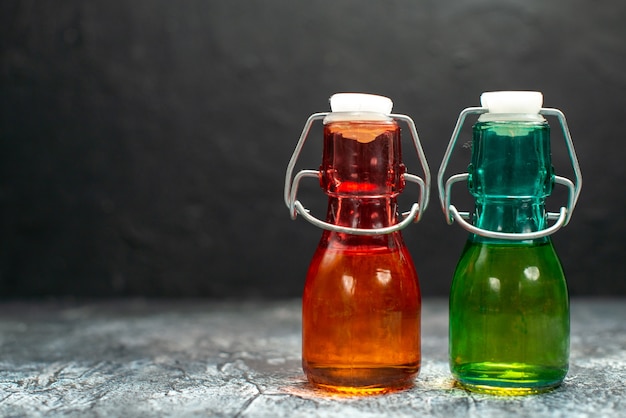 Free photo front view glass cans with liquid inside on the grey table