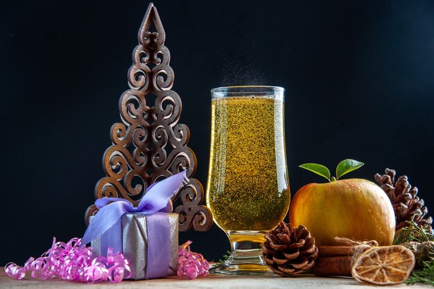 Front view glass of champagne with cones apple and presents on dark color drink party