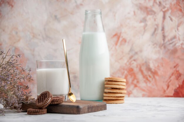 Вид спереди на стеклянную чашку и бутылку с молочным печеньем на деревянной доске цветок на ледяном фоне