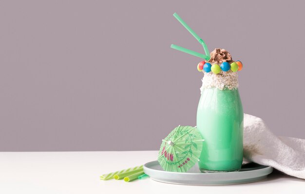 Front view of glass of dessert with colorful candy topping and umbrella