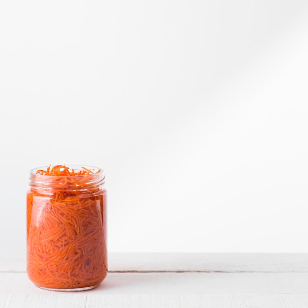 Free photo front view of glass jar with preserved chopped baby carrots and copy space