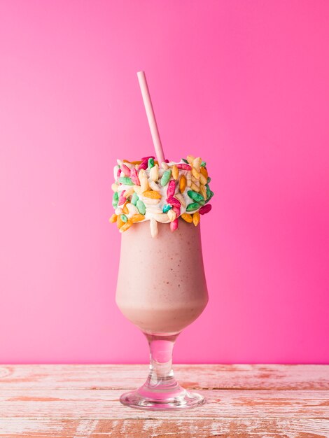 Front view of a glass of milkshake with pink background