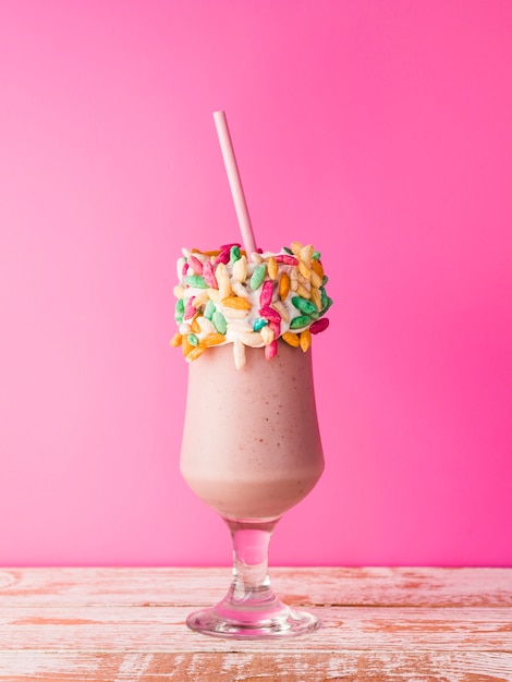 Front view of a glass of milkshake with pink background