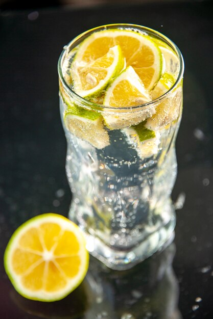 暗い写真のシャンパン ウォーター カクテル ドリンク レモネードにレモン スライスとソーダの正面ガラス