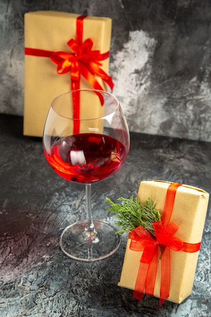 Free photo front view glass of wine gifts on dark background