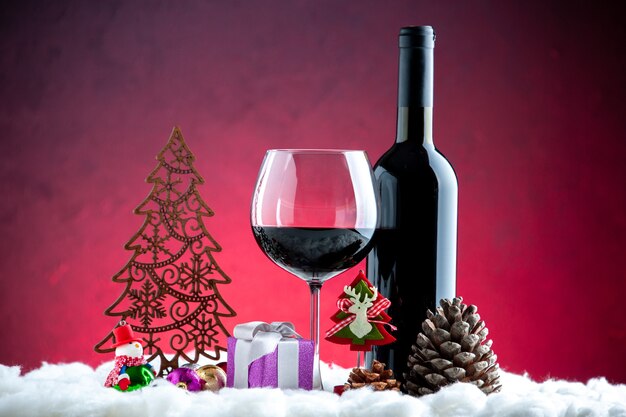 어두운 빨간색 배경에 와인 와인 병 크리스마스 장식 솔방울의 전면 보기