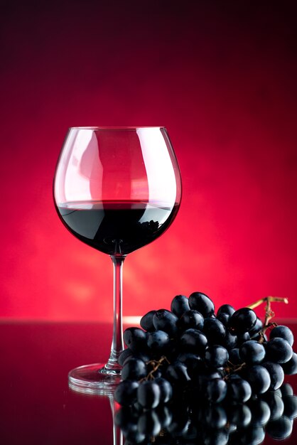 Front view glass of wine with grapes on pink wall a