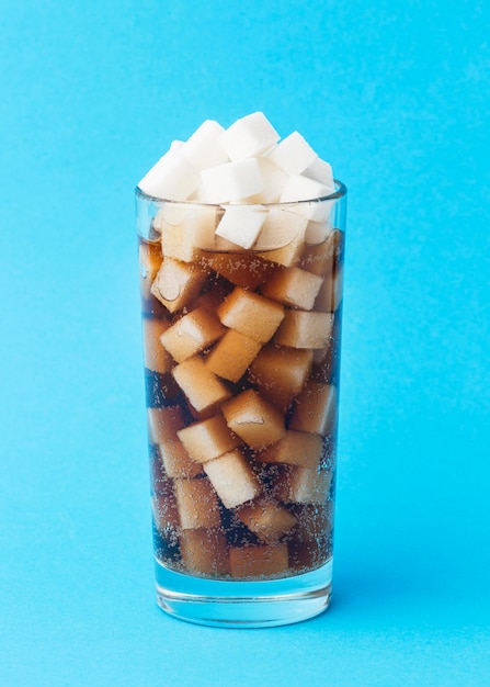 Вид спереди стекла с безалкогольным напитком и кубиками сахара