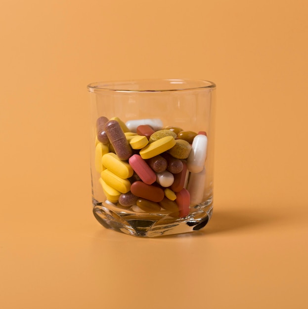 Free photo front view of glass with variety of pills