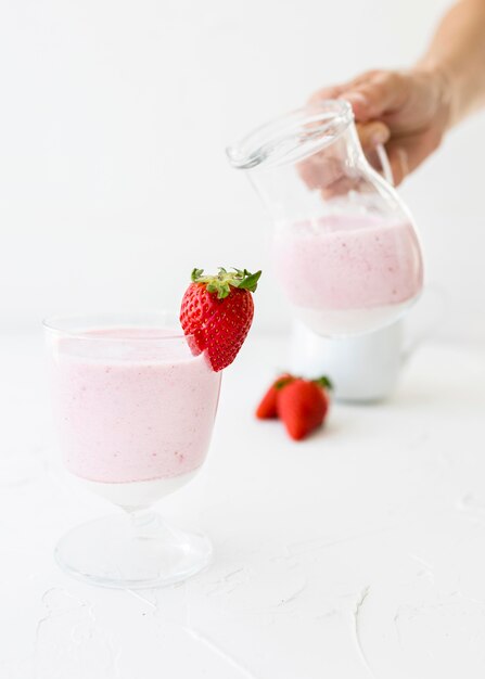 Front view glasses and jug of strawberry milkshake