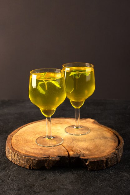 A front view glasses with juice lemon juice inside transparent glasses on the brown wooden desk