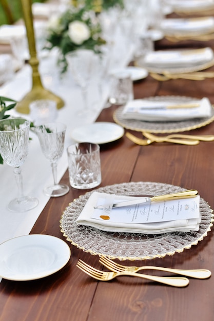 Front view of glassware and cutlery served on the wooden table and printed guest nameplate