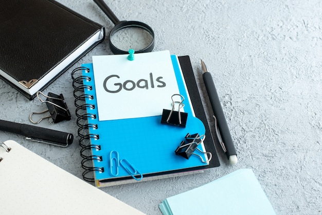 front view goals written note with notepad and pen on white background