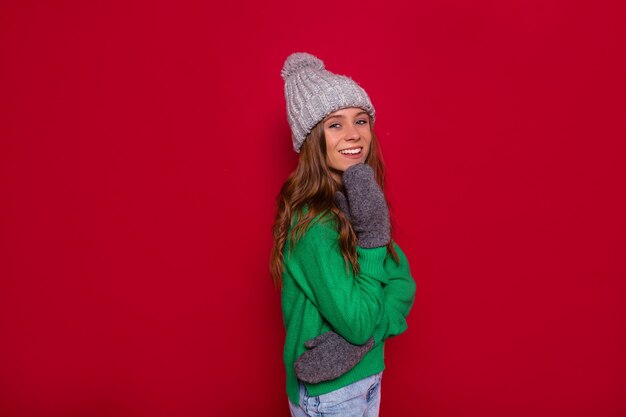니트 모자와 녹색 스웨터에 화려한 젊은 여자의 전면보기