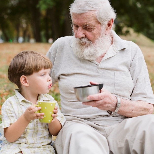 Front view grandpa and grandson drinking tea