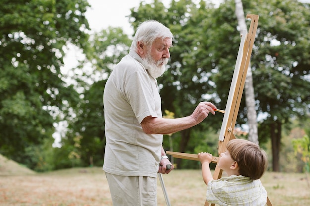 Front view grandson looking at grandpa painting