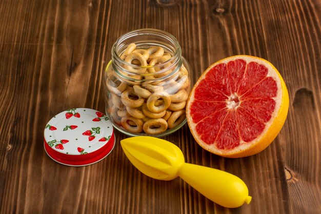 Front view grapefruit and crackers on brown desk