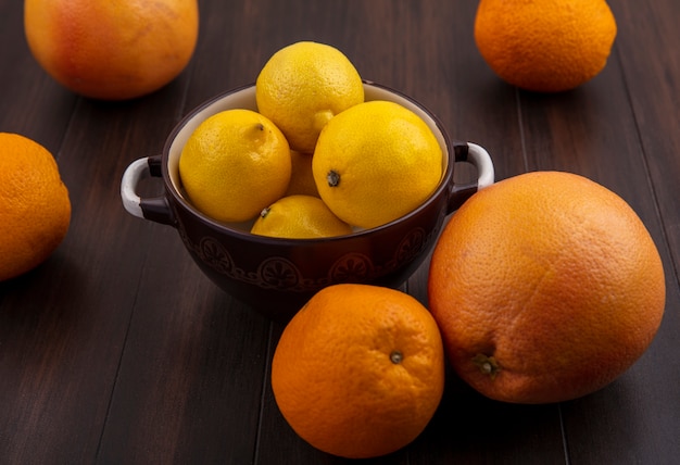 Foto gratuita pompelmo di vista frontale con arance e limoni in una casseruola su un fondo di legno