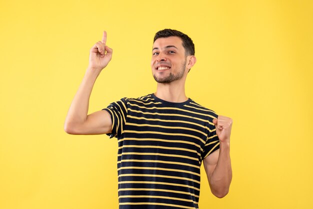 Front view gratified handsome male in black and white striped t-shirt yellow isolated background