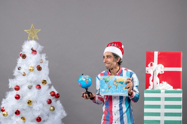 Front view gratified man holding world map and globe