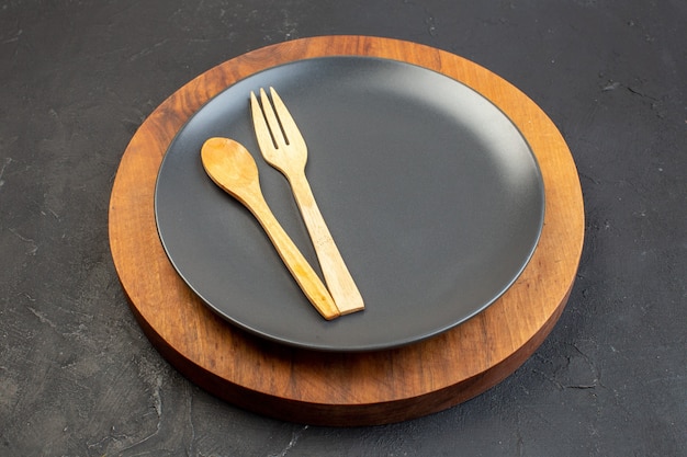 Front view gray plate on wooden cutting board dark surface