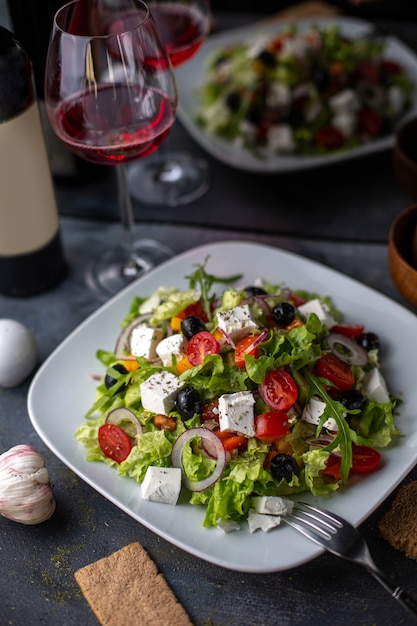 Вид спереди Греческий салат нарезанный овощной салат с помидорами, огурцами, белым сыром и оливками внутри белой тарелки с витаминами