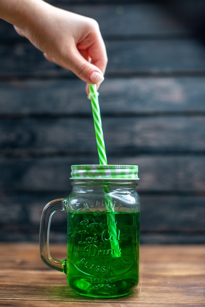 Бесплатное фото Зеленый яблочный сок, вид спереди, внутри банки с трубочкой на темном фруктовом напитке, цветная коктейль-бар