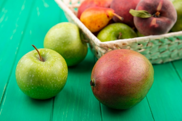 緑の表面にバケツに梨桃のようなさまざまな果物と緑のリンゴの正面図