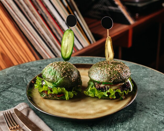 녹색 책상에 둥근 접시 안에 그린 샐러드와 전면보기 녹색 햄버거