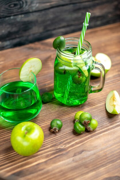 Front view green feijoa juice inside can with green apples on wooden desk bar fruit color drink photo cocktail