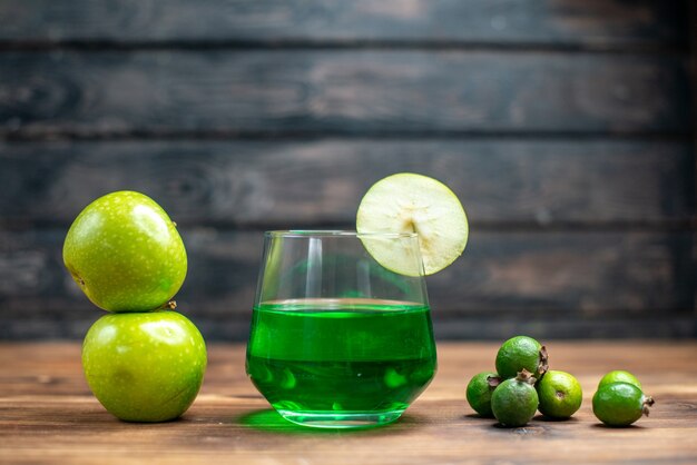 木製の机の上に緑のリンゴが入ったガラスの中の正面の緑のフェイジョア ジュース バー フルーツ カラー ドリンク フォト カクテル