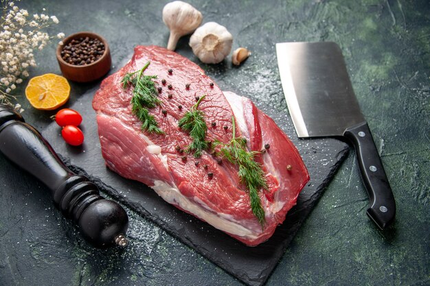 Front view of green on fresh red raw meat on cutting board and pepper lemon black hammer flower ax on green black mix color background